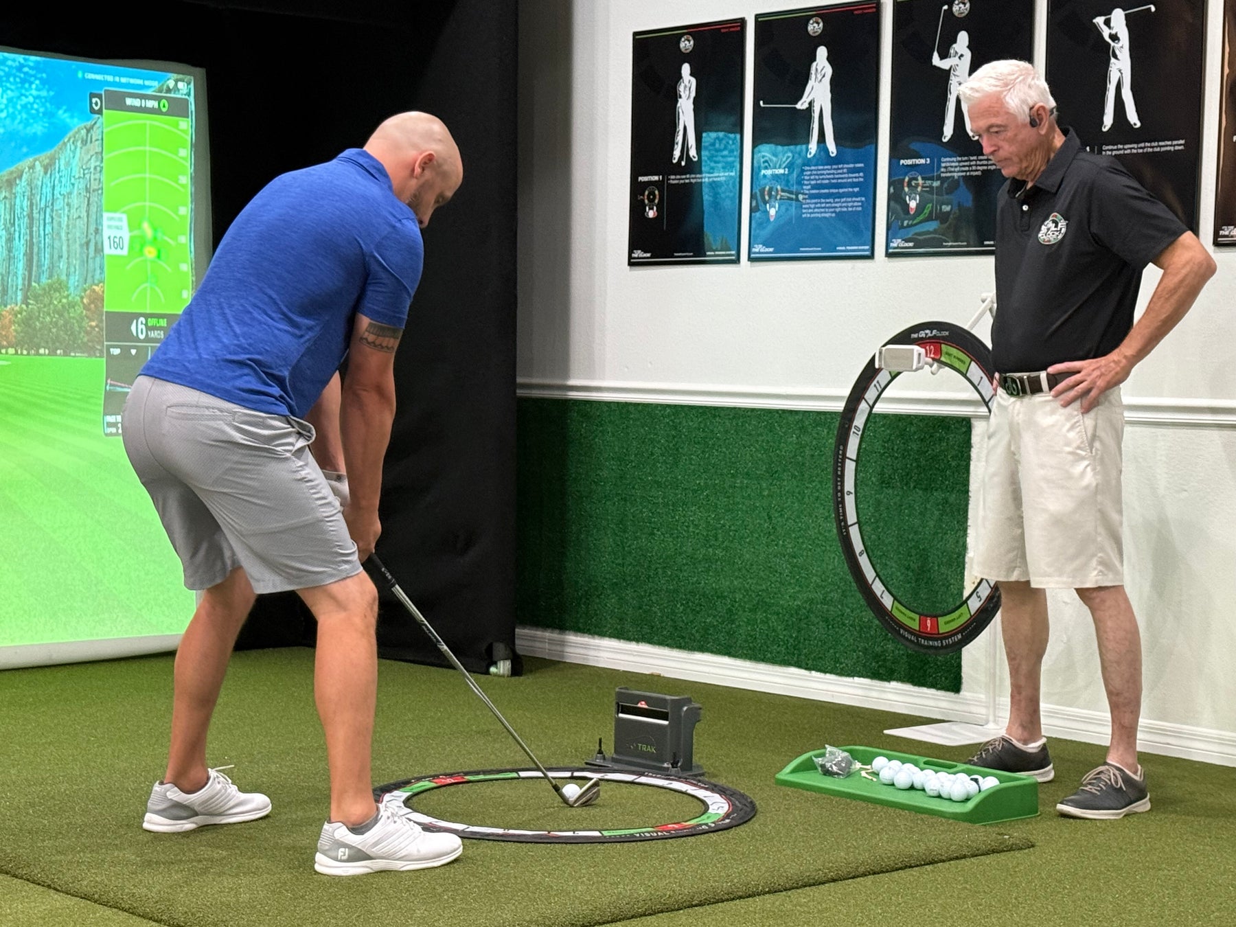 A golfer using The Golf Clock in a lesson bay at KP Golf Studio, the ring lying flat around the ball